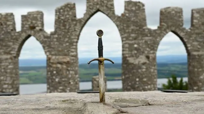 The dagger standing upright in stone, framed by ruined castle arches